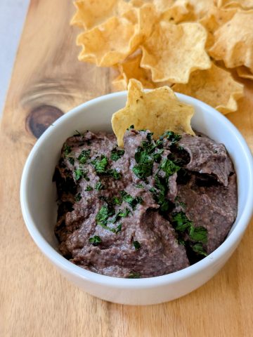 Homemade Black Bean Dip with Tortilla Chips in a White Bowl