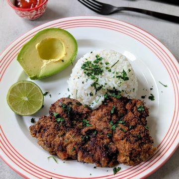Crispy and Golden Brown Breaded Steak, Served with White Rice and Avocado on the Side
